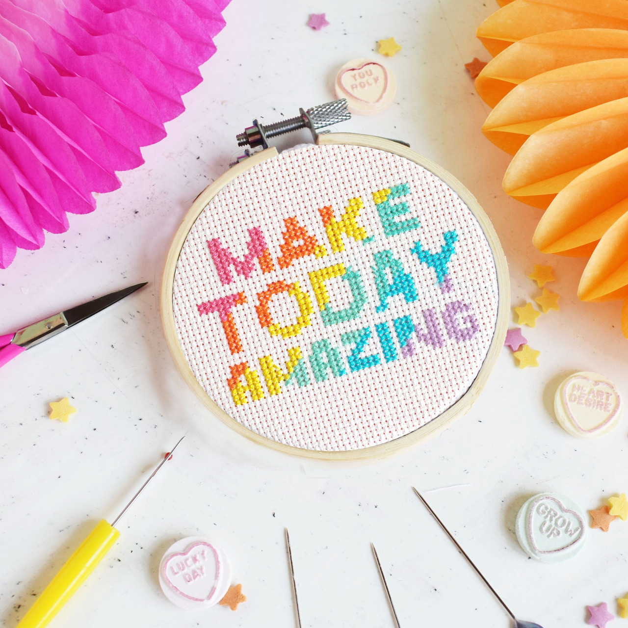 Colorful cross-stitch embroidery hoop with the words Make Today Amazing on a white craft table