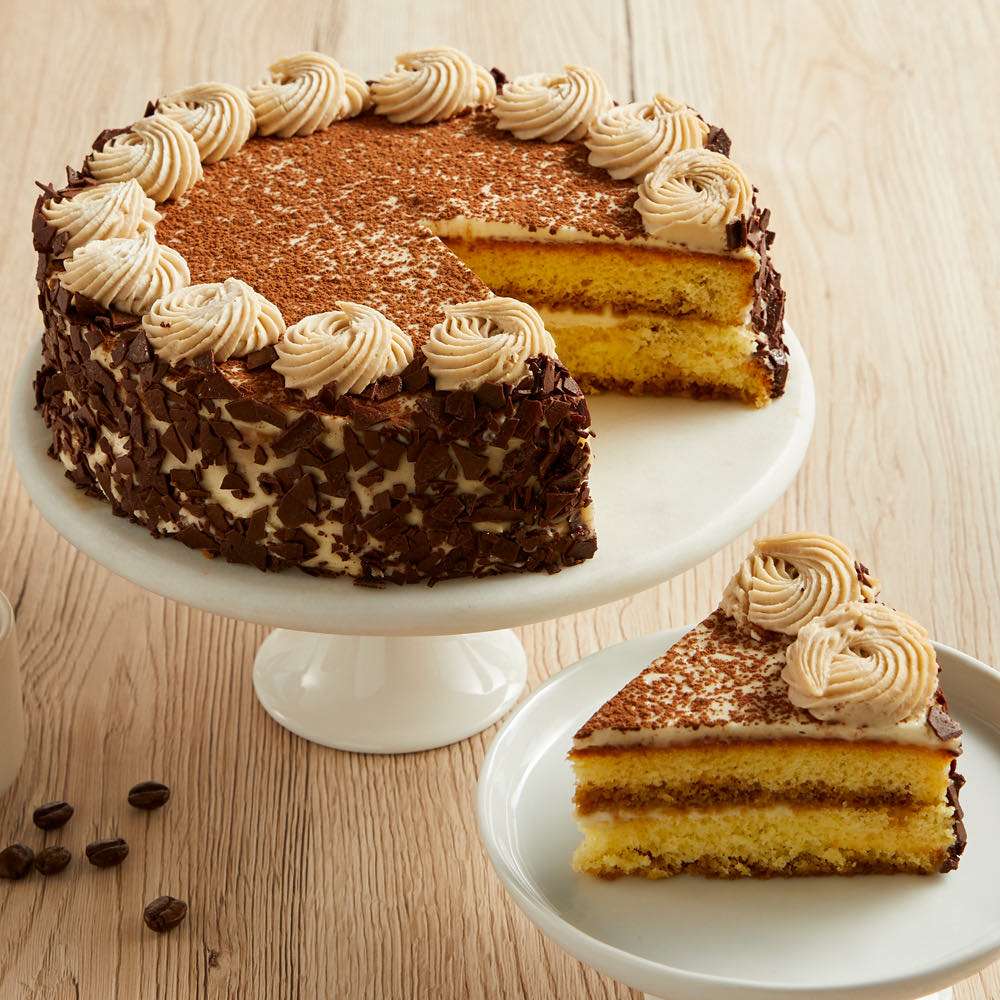 Chocolate layer cake with cream rosettes and a slice on white stand