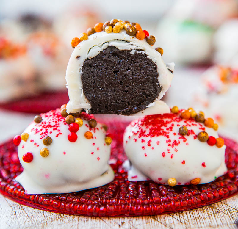 Three chocolate cake truffles with white frosting and colorful sprinkles on red plate