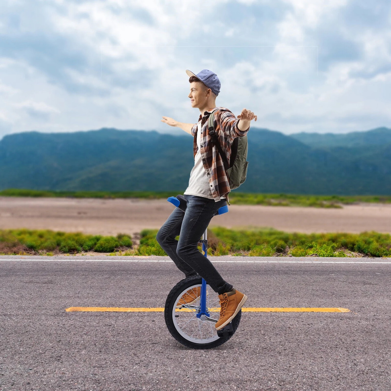 Person balancing on unicycle on road with mountain backdrop