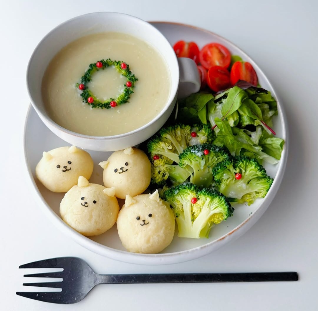White plate with kawaii animal-shaped buns, broccoli, tomatoes, and soup with wreath decoration