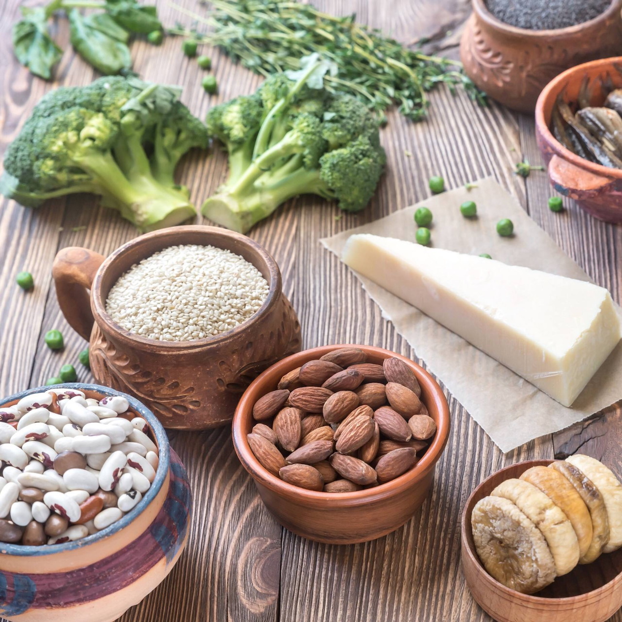 Flat lay of healthy foods: broccoli, almonds, beans, quinoa, cheese, banana on striped surface