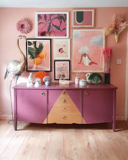 Pink sideboard with gallery wall of art prints, flamingo sculptures, and decorative objects against a pink wall