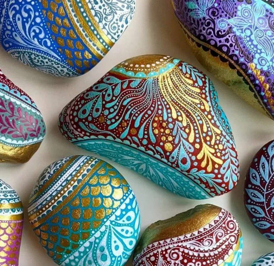 Collection of smooth stones hand-painted with colorful mandala and paisley patterns in turquoise, gold, and purple