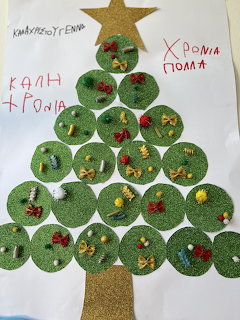 Handmade Christmas tree from green paper circles with mini decorations and Greek holiday text on white paper