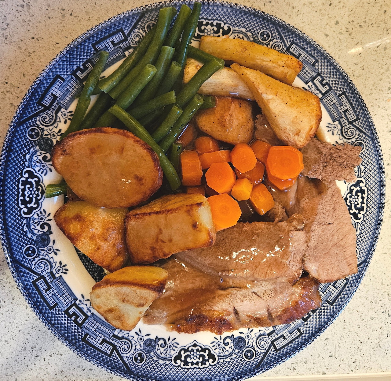 Roast lamb dinner with vegetables and gravy on decorative plate
