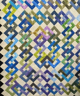 Colorful patchwork quilt with diamond pattern in blue, green, yellow, purple, and cream squares
