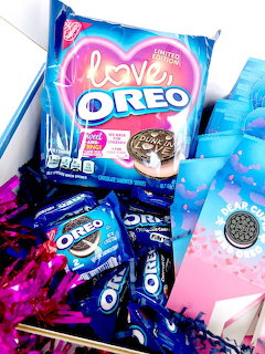 Pink heart-shaped Love Oreo package with cookies scattered around on colorful background