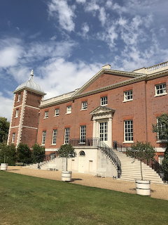 Red brick Georgian mansion with turrets and stone staircase under a blue sky