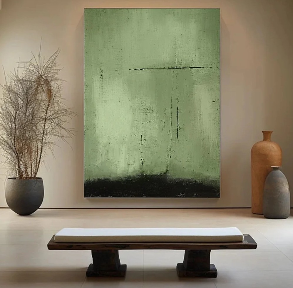 Green abstract painting with textured surface and dark bottom section displayed on beige wall with decorative elements