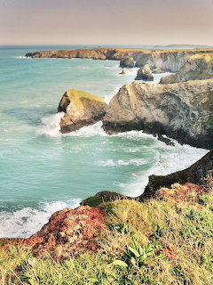 Rocky coastal cliffs and sea stacks at Bedruthan Steps with turquoise ocean and green vegetation