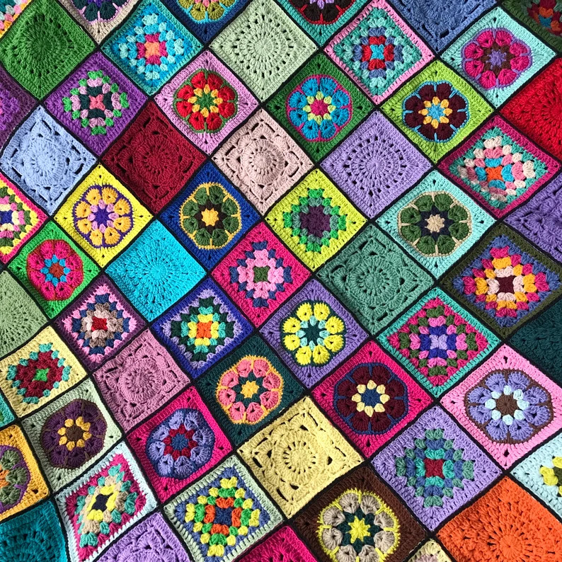 Colorful crocheted granny square blanket with floral patterns in rainbow hues
