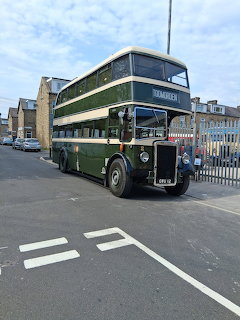 Vintage green Leyland double-decker bus parked on a street with buildings behind