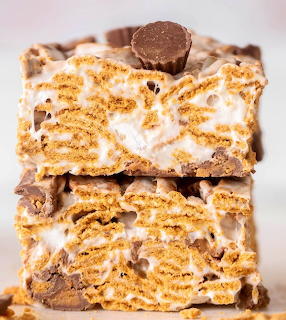 Three stacked s'mores dessert bars with graham cracker base, chocolate, and toasted marshmallow drizzle