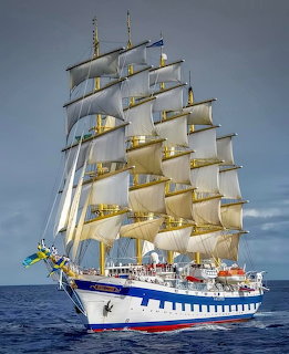 Five-masted Royal Clipper tall ship sailing with full white sails on blue sea