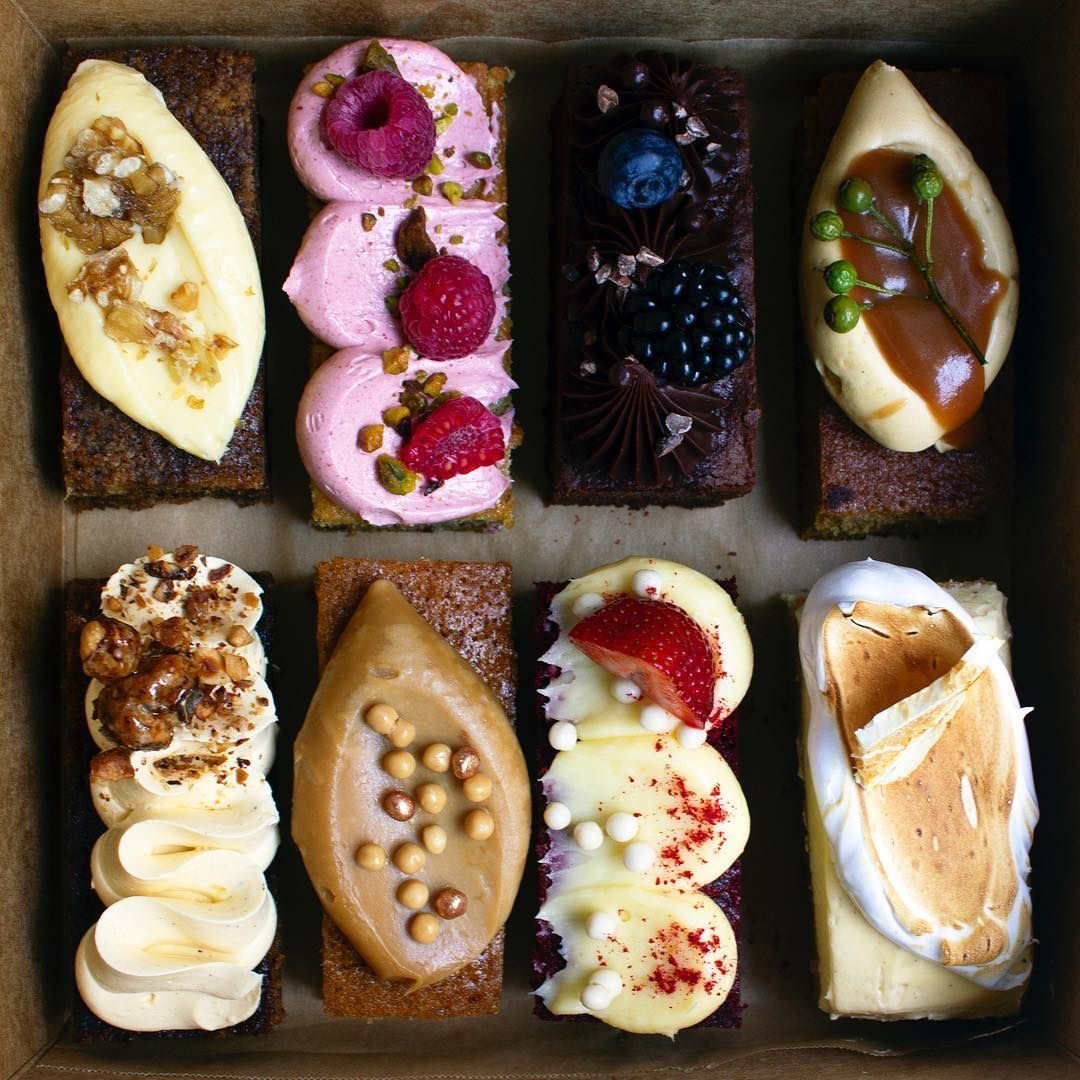 Box of assorted eclairs with fruit, chocolate, cream, and caramel toppings