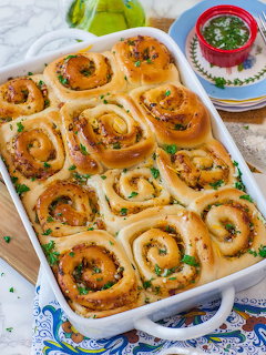 Twelve golden bacon cheddar spiral rolls in white ceramic baking dish