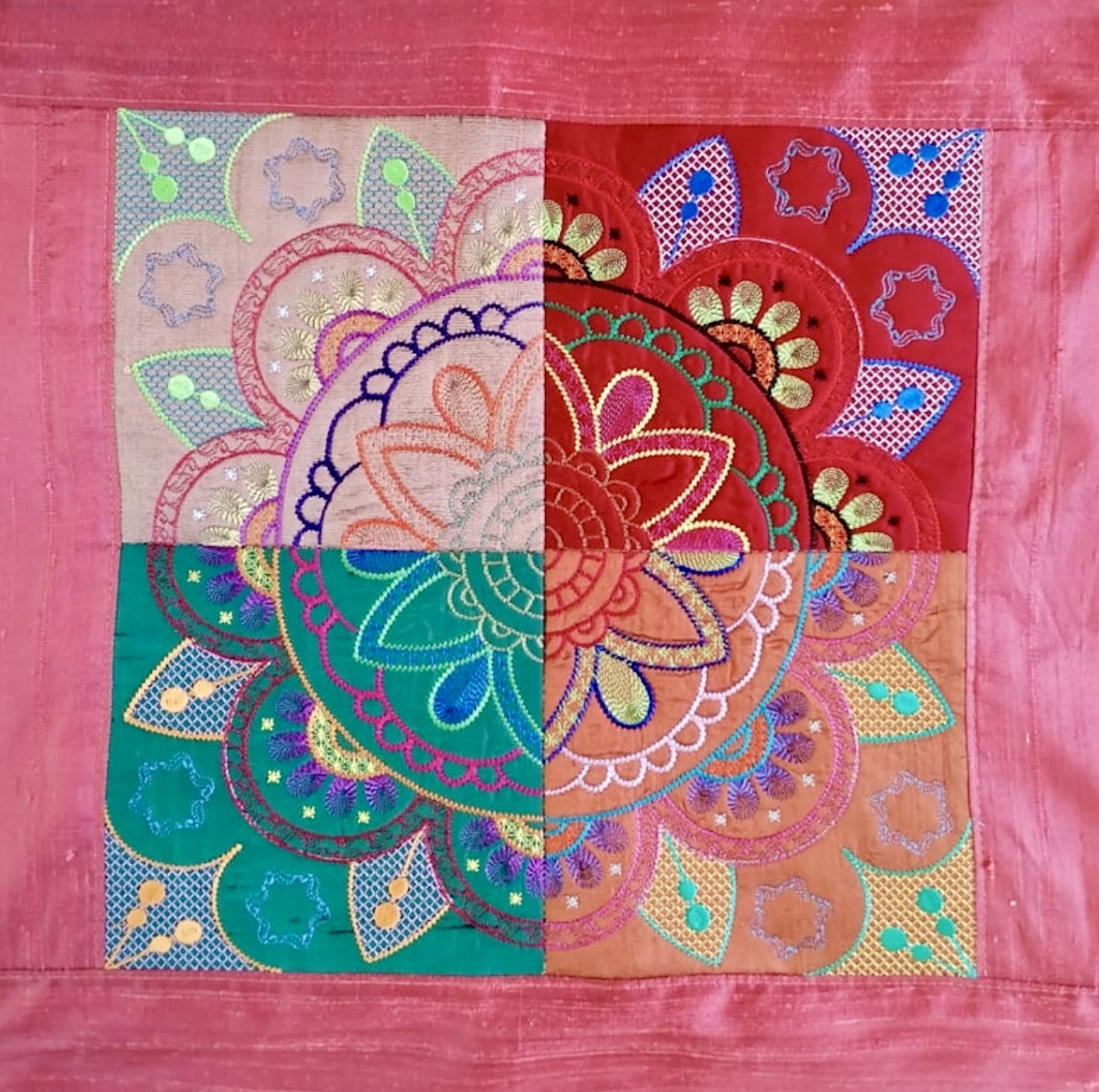 Embroidered mandala quilt square with colorful floral patterns in four quadrants