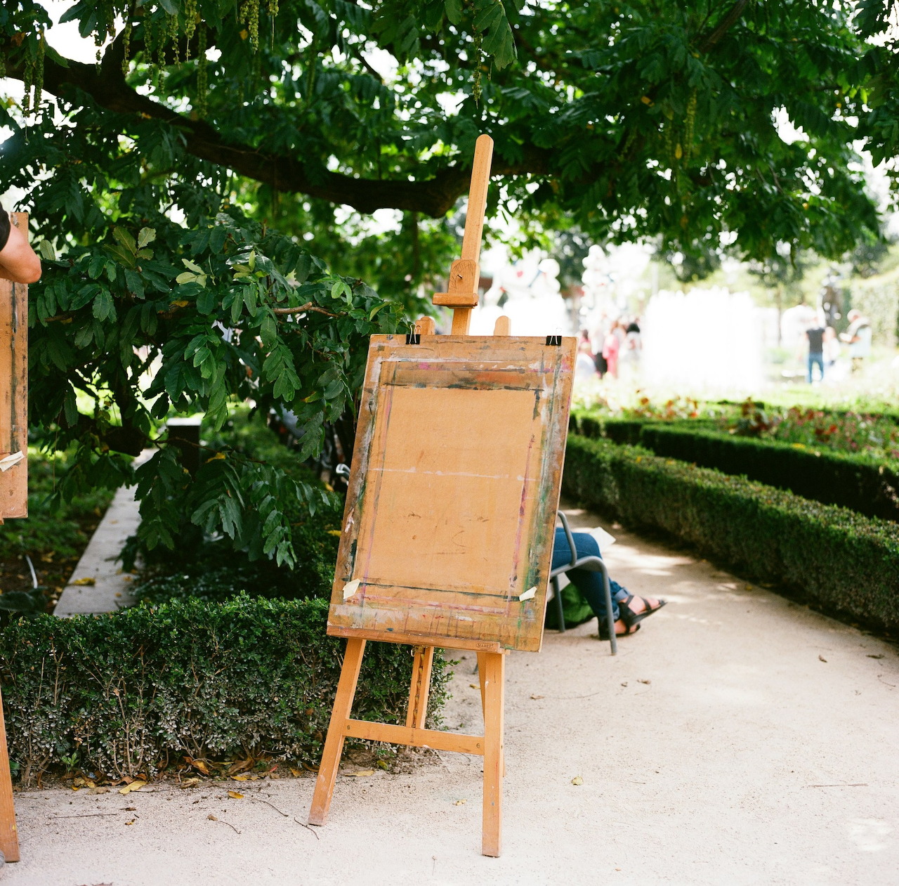 Wooden easel on a garden path beneath leafy trees