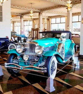 Turquoise 1930 Duesenberg Model J convertible sedan on display in a classic car museum