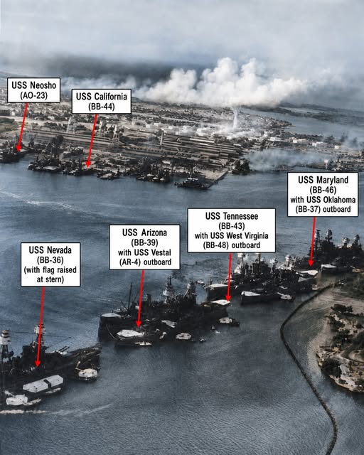 Aerial photo of several military warships docked in a foggy harbor with identification labels