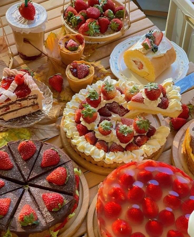 Assorted fruit tarts and cakes with strawberries and berries on wooden table