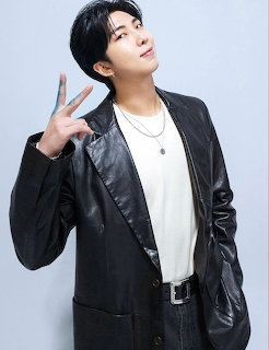 Young man in a black leather jacket and white shirt making a peace sign in a studio portrait.
