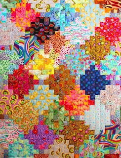 Colorful patchwork quilt with hexagonal patches in various bright patterns and colors arranged in a decorative layout