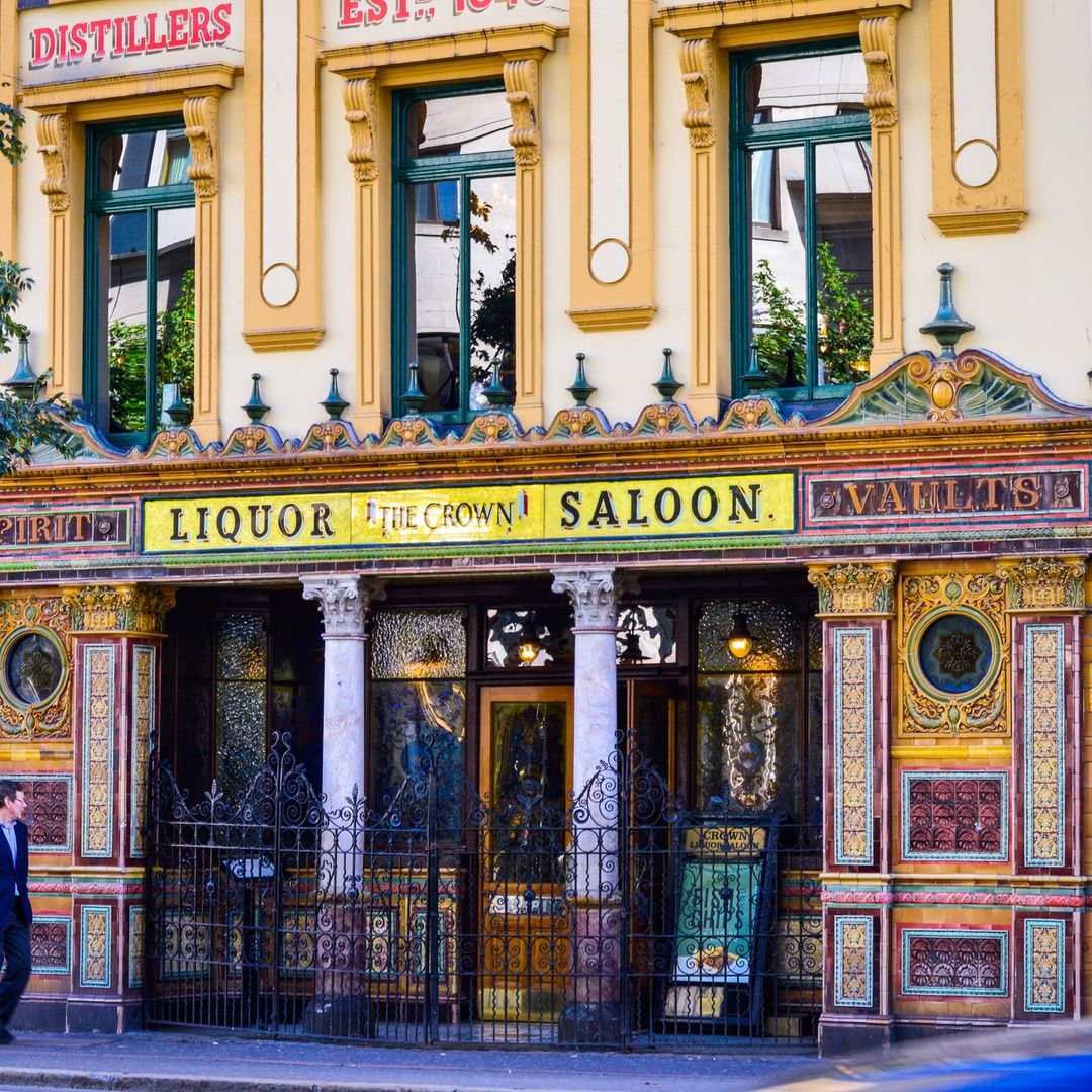 Ornate Victorian pub front with decorative tiles, stained glass, and Crown Saloon signage in Belfast
