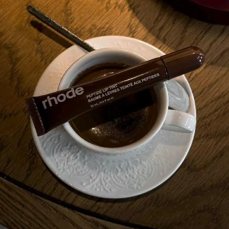 Espresso cup with lipgloss tube on wooden table
