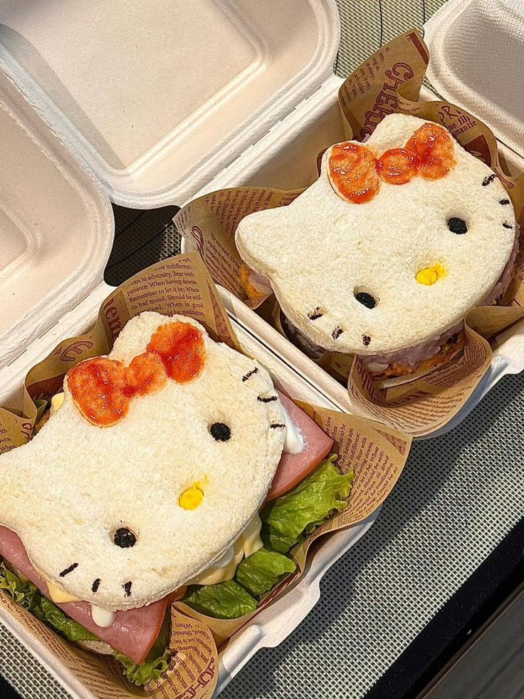 Two Hello Kitty face-shaped sandwiches with tomato bows, ham and lettuce filling, in takeout boxes