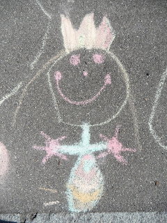 Colorful chalk drawing of a smiling princess with crown and dress on gray sidewalk pavement