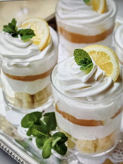 Three layered cream desserts in glass cups garnished with lemon and mint