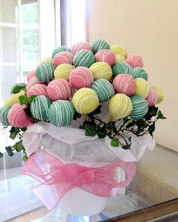 Bouquet of pastel-colored striped cake pops wrapped in white tissue and pink ribbon with greenery