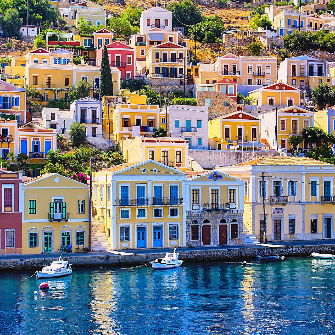 Colorful houses on hillside by Mediterranean harbor with boats in turquoise water