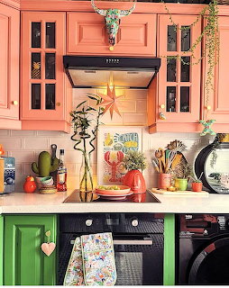 Colorful kitchen with coral pink cabinets, green island, longhorn skull above stove, and eclectic Southwestern decor