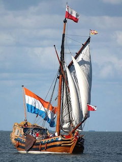 Historic Dutch tall ship with white sails and Dutch flag sailing on grey sea