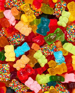Colorful gummy bear candies mixed with rainbow sprinkle-covered sweets in various bright colors