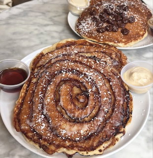 Spiral pancake with powdered sugar on a plate, served with syrup and butter