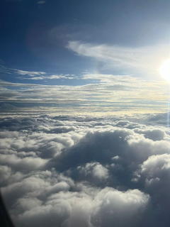 Sunlit cloud layer viewed from above with blue sky and thin wispy clouds