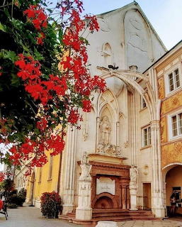 White baroque church with red autumn leaves in foreground, yellow buildings on sides