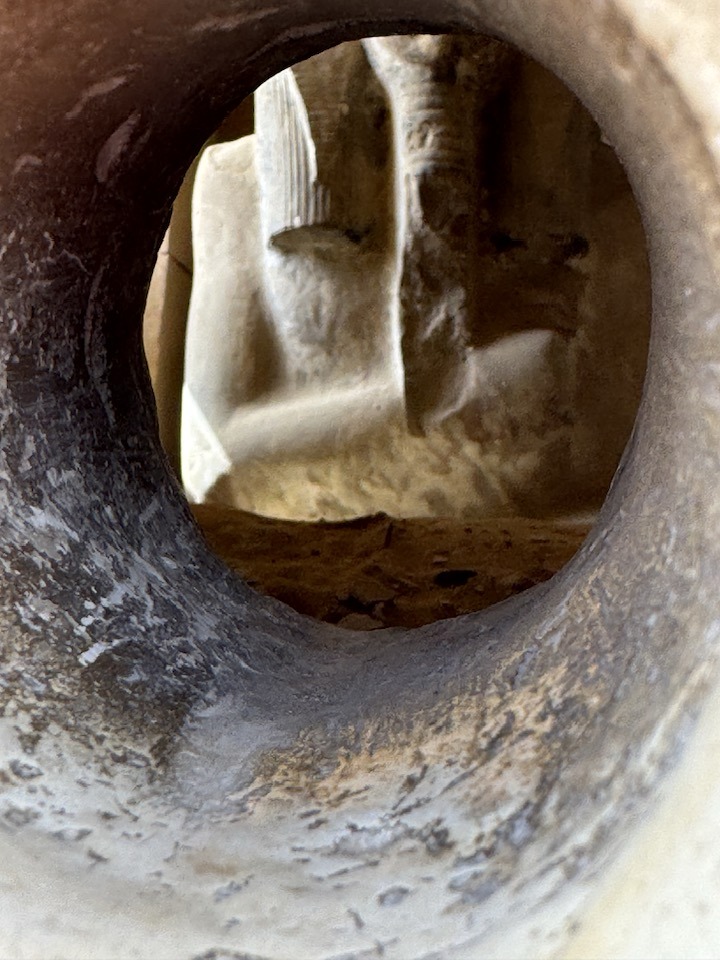 Ancient Egyptian statue feet seen through a circular stone opening