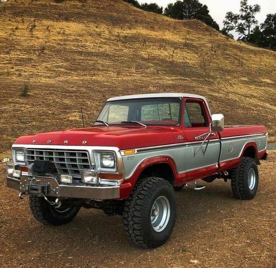 Red and silver vintage Ford pickup truck parked outdoors on a dirt road