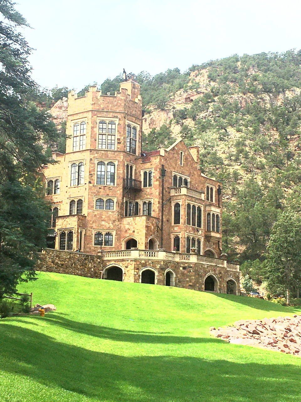 Historic stone castle with towers on grassy hill backed by forest