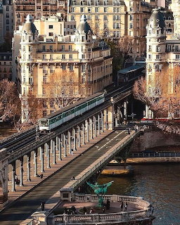 Train crossing Pont Bir-Hakeim bridge in Paris with historic buildings and river