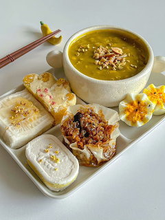Bowl of yellow soup with rice cakes, grilled mochi, and corn on a serving tray