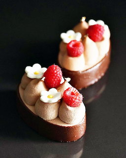 Two chocolate mousse desserts with strawberries and white flowers on dark background