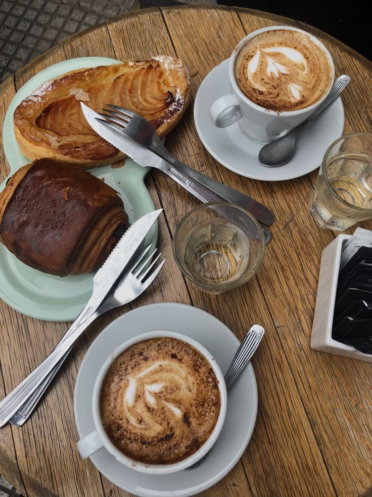 Latte with foam art next to assorted pastries in a cozy cafe setting
