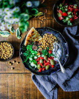Ethiopian food platter with chickpeas, vegetables, tomatoes and bread on dark plate with wooden table background