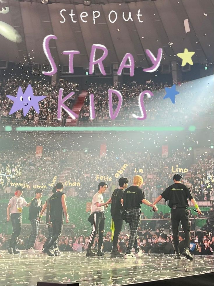 Stray Kids members on stage during a live concert with crowd and group name displayed overhead